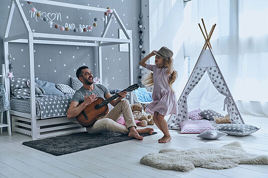 Vater und Tochter singen und Tanzen im Kinderzimmer.